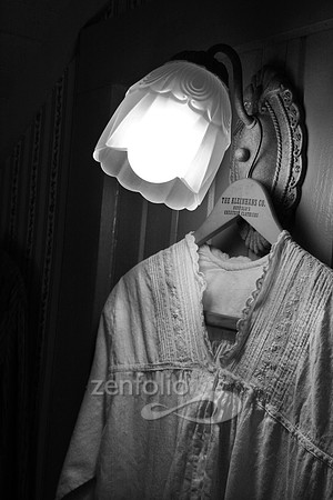 Color photograph of a soft glow of a vintage lamp on an antique nightgown by Crystal Nederman